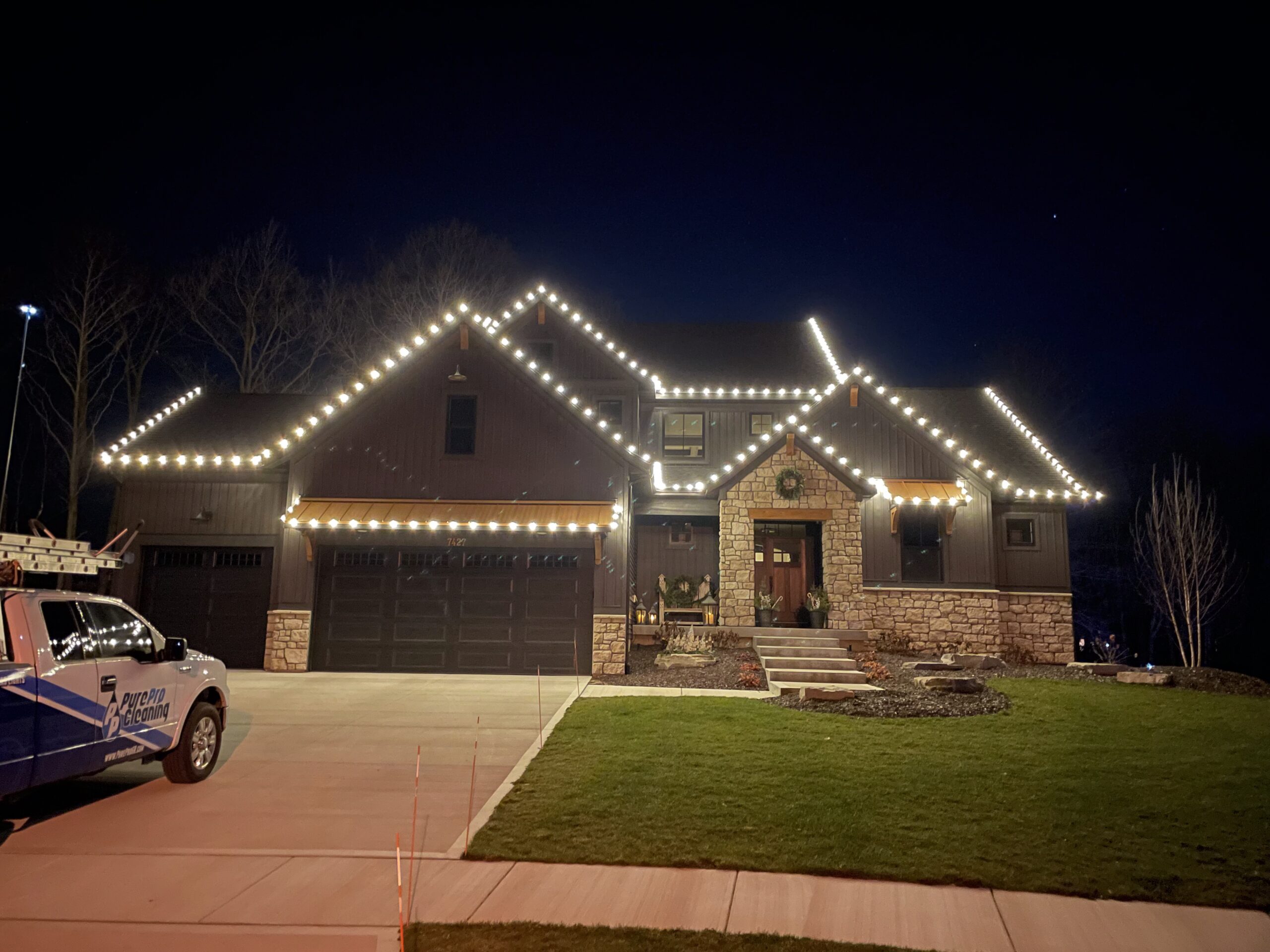 A house at night with multicolored string lights outlining the roof, surrounded by bare trees and a dark sky—perfectly showcasing the results of expert window cleaning Allendale Michigan residents trust.